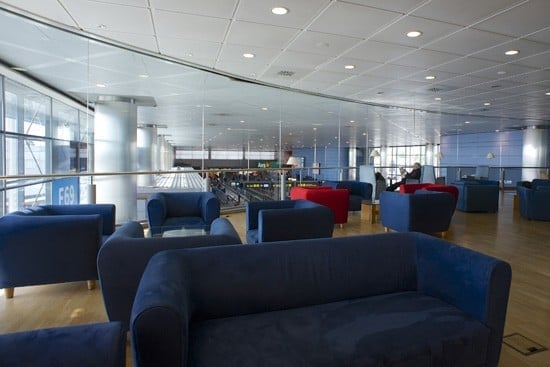 The seating area in Sala Puerta Del Sol at Madrid Barajas Airport offers comfortable chairs with views of the terminal below.
