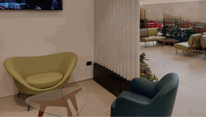 The seating area in Pergolesi Classic Lounge at Malpensa Airport features comfortable chairs and a small table, offering a relaxing space for travelers.