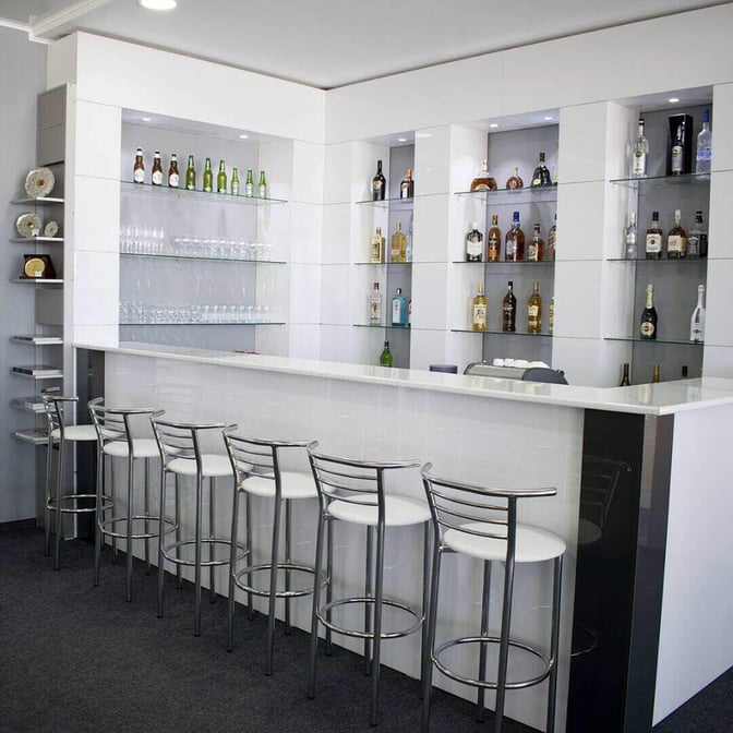 The bar area in the Manas International Airport Business Lounge features a selection of spirits and beers with high stool seating.
