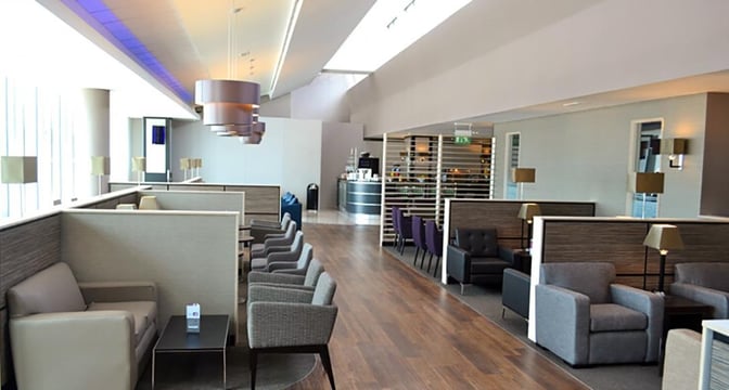The Aspire Lounge at Manchester Airport features semi-private seating areas with armchairs and tables, offering a comfortable space for travelers.