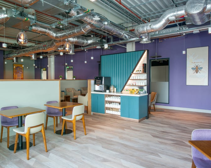 The Aspire Lounge at Manchester Airport features a self-serve beverage station with seating areas for dining and relaxation.