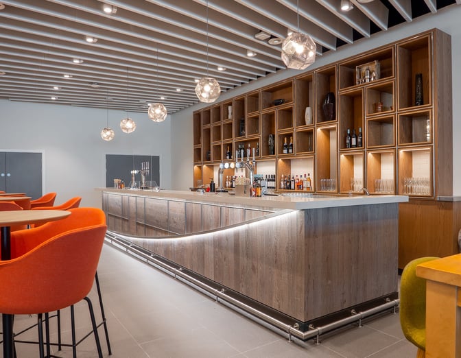 The Escape Lounge at Manchester Airport features a bar with complimentary beverages and seating, offering a relaxing pre-flight experience.