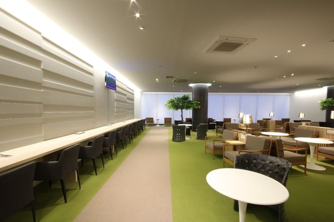 The CIP Lounge at Mandalay International Airport features a spacious seating area with tables, chairs, and a long work counter.