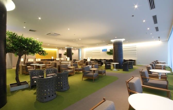 The CIP Lounge at Mandalay International Airport features spacious seating areas with tables, armchairs, and decorative plants for relaxation.