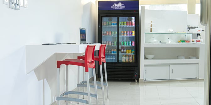The Executivo 2000 lounge at Maputo International Airport features a beverage fridge, counter seating, and a self-serve snack area.