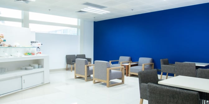 The lounge at Maputo International Airport features a seating area with armchairs and tables, alongside a self-serve snack station.