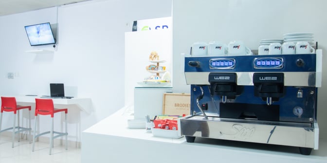 The lounge at Maputo International Airport features a coffee station with an espresso machine and a seating area with workstations.