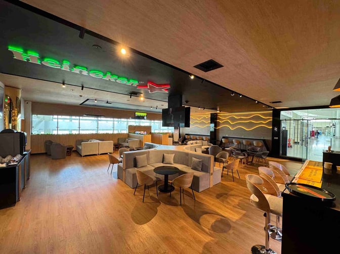 The Bomgarfo Lounge at Maputo International Airport features a seating area with couches and tables, adjacent to a bar counter.