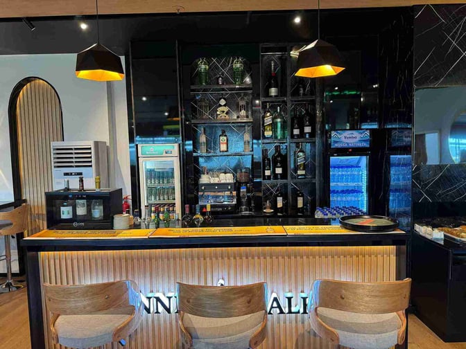 The bar at Bomgarfo Lounge in Maputo International Airport offers a selection of spirits and beverages with counter seating.