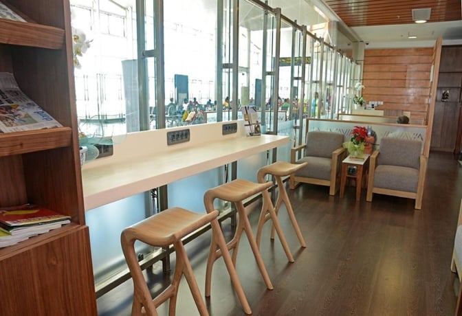 The Executivo 2000 Lounge at Maputo International Airport features a seating area with bar stools, armchairs, and accessible power outlets.