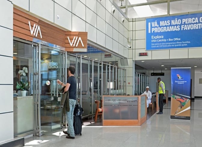 The Executivo 2000 Lounge entrance at Maputo International Airport features glass doors and is located near a seating area and airline signage.