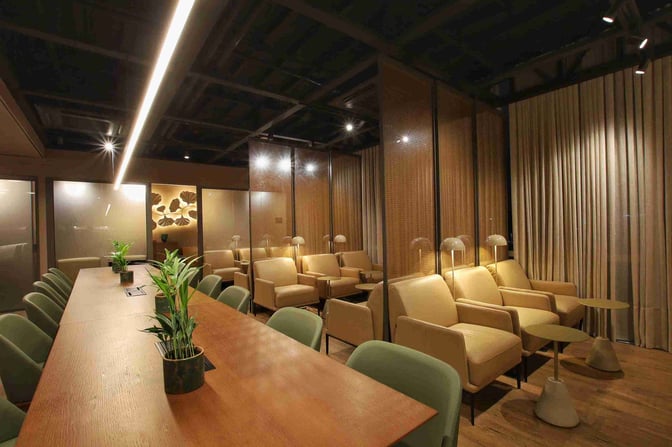 The W Lounge Cuiabá features a seating area with armchairs, small tables, and a communal table with chairs and plants.