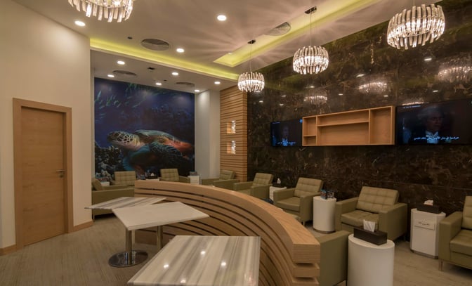 The Pearl Lounge at Marsa Alam International Airport features comfortable seating with individual tables and a large wall mural of marine life.