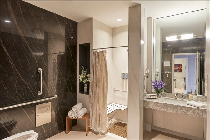 The Club LAS at McCarran International Airport features a private bathroom with a shower area, accessible amenities, and a vanity sink.