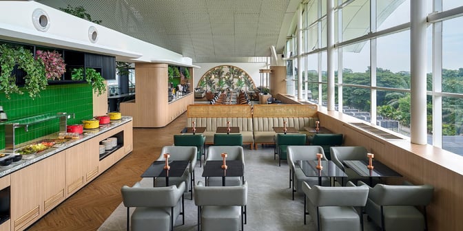 The Plaza Premium Lounge at Kualanamu International Airport features a self-serve food area and varied seating with large windows.