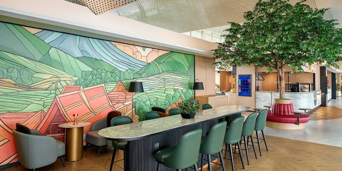 The Plaza Premium Lounge at Kualanamu International Airport features a seating area with a long communal table and a vibrant mural.