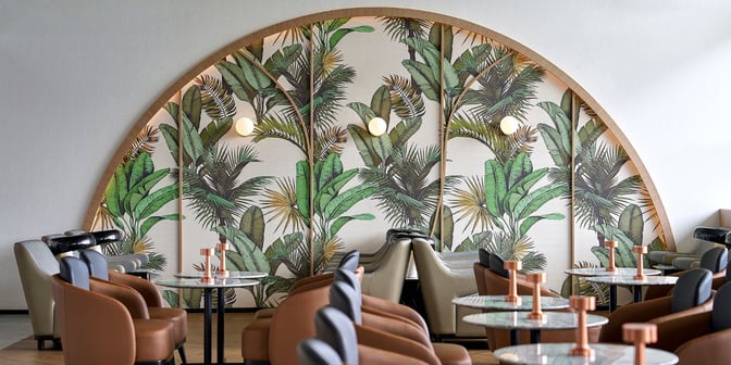 Seating area in Plaza Premium Lounge at Kualanamu International Airport features comfortable chairs and tables with a decorative wall backdrop.