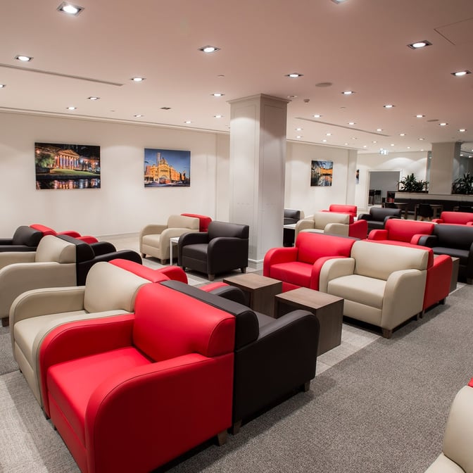 The Marhaba Lounge at Melbourne Airport features a seating area with armchairs and small tables, providing a comfortable waiting space.