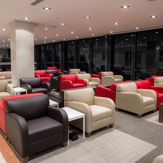 The seating area in Marhaba Lounge at Melbourne Airport features rows of armchairs with side tables, offering a comfortable waiting space.