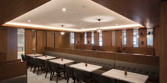 Booth seating in the Plaza Premium Lounge at Melbourne Airport offers semi-private dining with tables and cushioned benches.