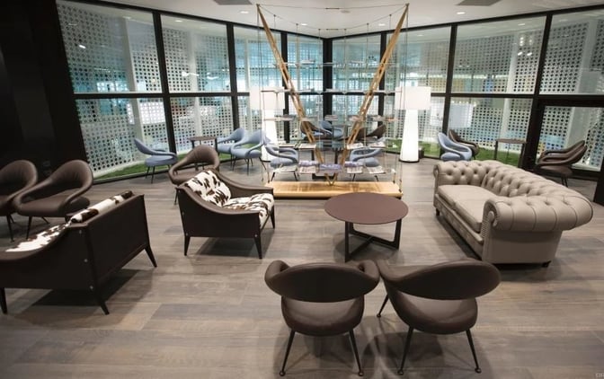 The seating area at Club S.E.A. Sala Leonardo in Milan Linate Airport offers various chairs and sofas for passenger relaxation.