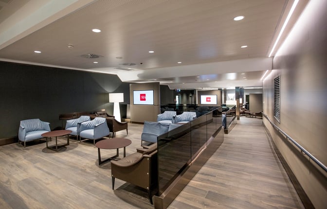The seating area at Club S.E.A. Sala Leonardo in Milan Linate Airport features comfortable chairs and tables for passenger relaxation.