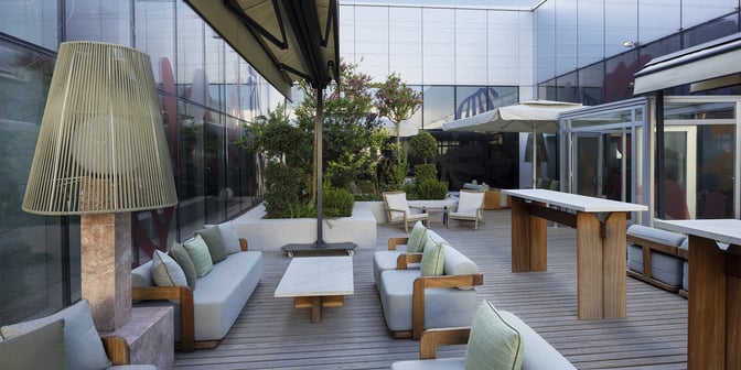 The outdoor seating area at Primeclass Lounge, Milas–Bodrum Airport, features cushioned chairs, tables, and greenery for relaxation.