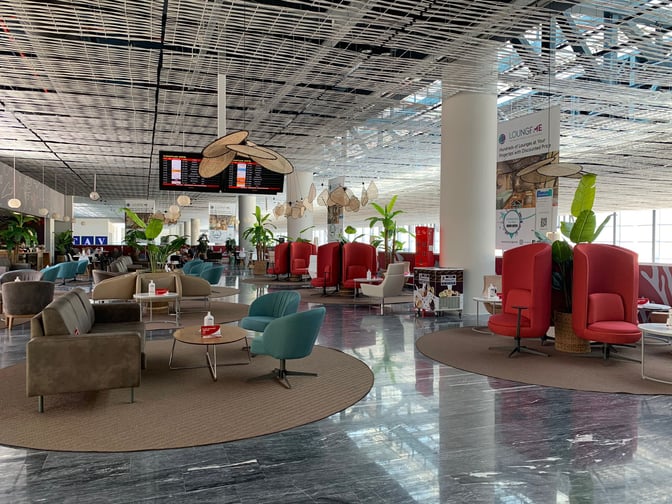 The Primeclass Lounge at Milas–Bodrum Airport features varied seating arrangements with tables, surrounded by informational displays and flight status screens.