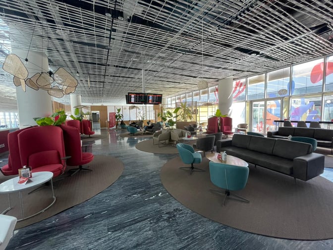 The Primeclass Lounge at Milas–Bodrum Airport features varied seating options with tables, providing a comfortable waiting area for travelers.