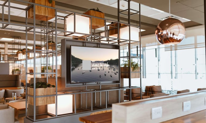 The Ezeiza Lounge features a seating area with tables, chairs, and a television, providing a comfortable space for travelers.