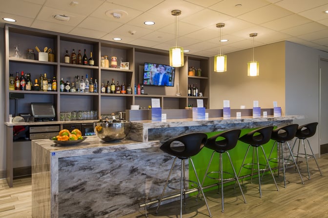 The Escape Lounge bar at Minneapolis-Saint Paul International Airport offers a selection of spirits with counter seating and a television.