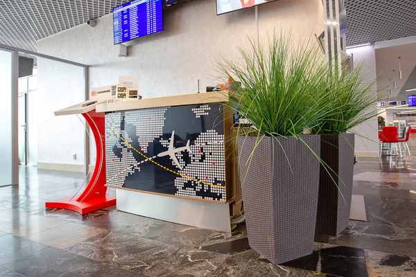 The reception desk at Minsk National Airport's Domestic Business Lounge features a decorative panel and is located near flight information displays.