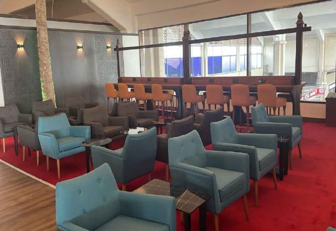 The seating area in the Bosphorus Lounge at Moi International Airport features armchairs and high stools with views of the terminal.