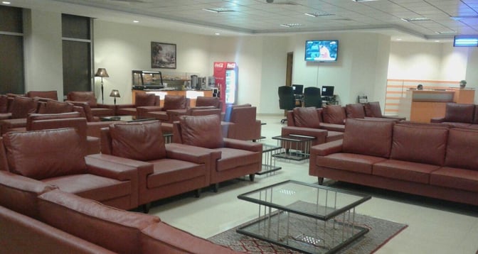 The CIP Lounge at Multan International Airport features seating areas with armchairs, a self-serve food station, and a television.