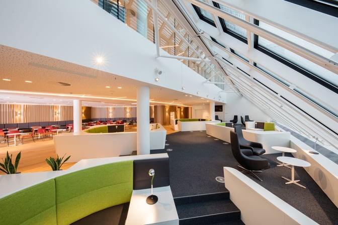 The seating area in Airport Lounge World at Munich Airport features semi-private booths and individual chairs with tables for relaxation.