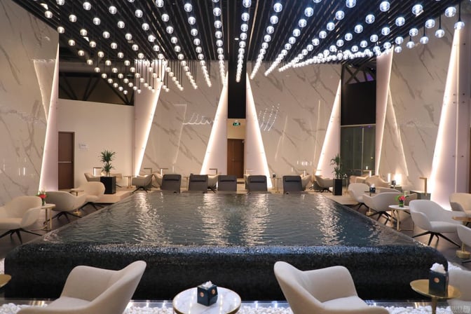 The Majan Lounge at Muscat International Airport features a central water feature surrounded by seating areas for relaxation and socializing.