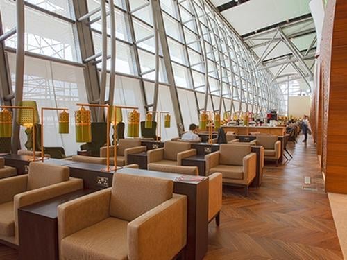 Seating area in the Primeclass Lounge at Muscat International Airport offers individual chairs with side tables and power outlets near large windows.