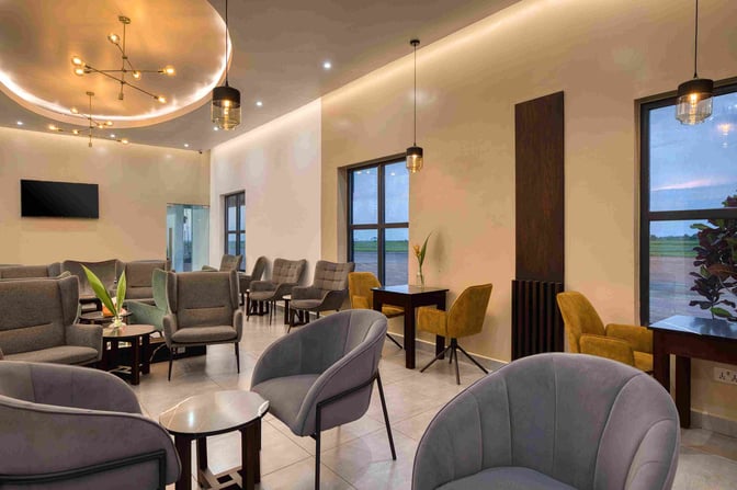 The Serengeti Lounge at Mwanza Airport features a seating area with armchairs and tables, offering views of the runway.