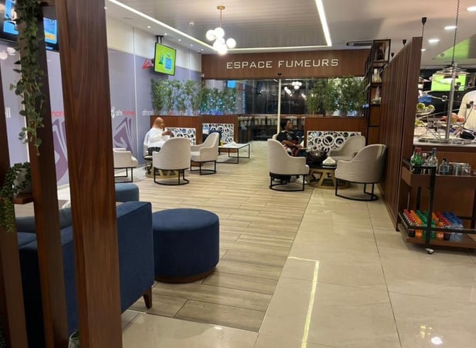 The Le Meilleur VIP Lounge at N'Djili International Airport features a seating area with chairs and tables near a refreshment station.