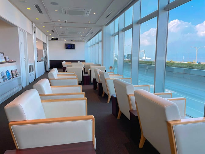 The Business Lounge AZALEA at Nagasaki Airport features comfortable seating with large windows offering views of the airport runway.