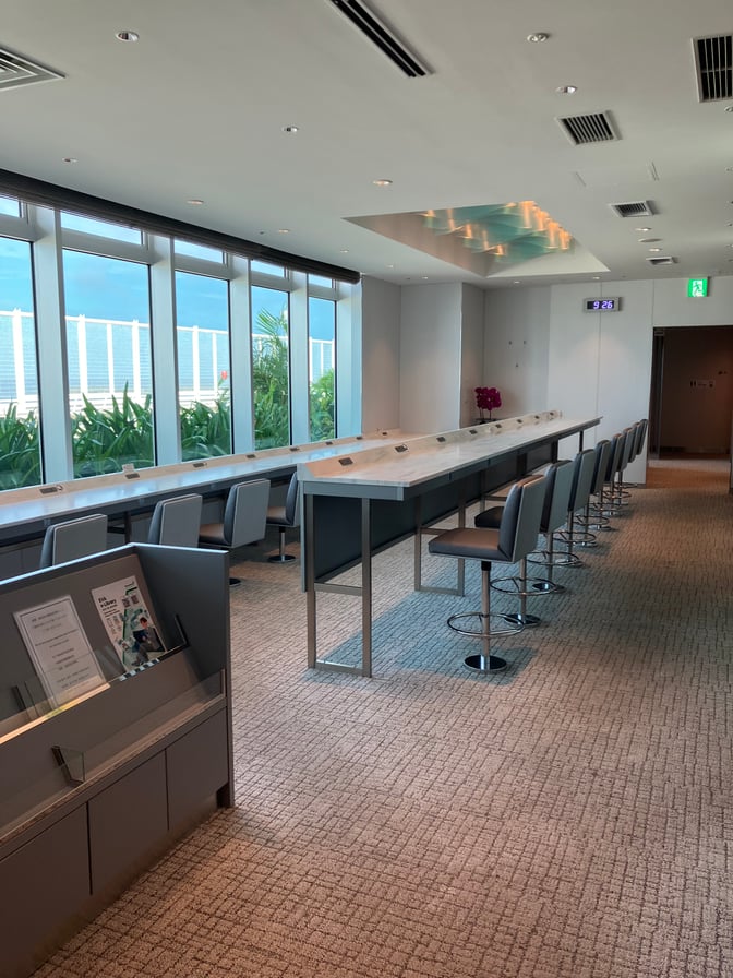 The seating area at Lounge RYURIN, Naha Airport, features a long counter with bar stools and large windows offering views.
