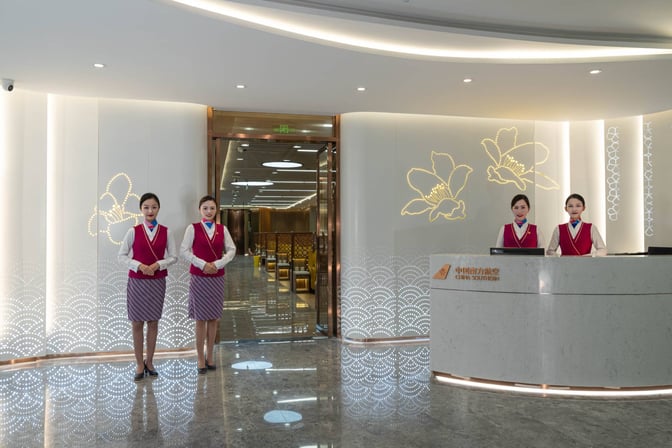 The entrance to China Southern Airlines V5 Lounge at Nanjing Lukou International Airport features a reception desk and welcoming staff.