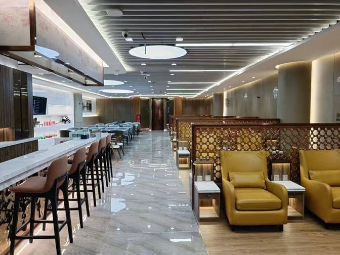 The lounge features a bar with high seating and a seating area with armchairs and partitioned booths for privacy.