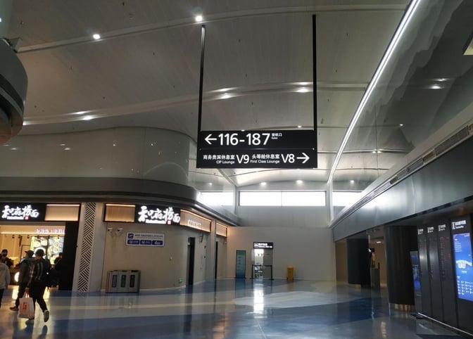 The signage directs travelers to the V9 Business Lounge and V8 First Class Lounge at Nanjing Lukou International Airport.