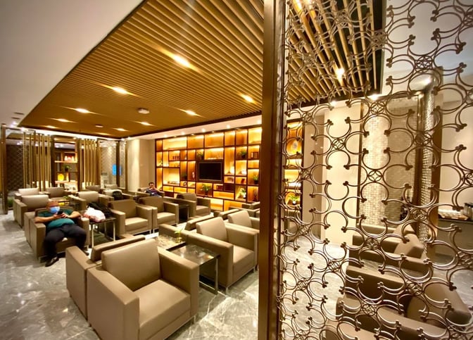 The V9 Business Lounge at Nanjing Lukou International Airport features a seating area with armchairs and a wall-mounted television.