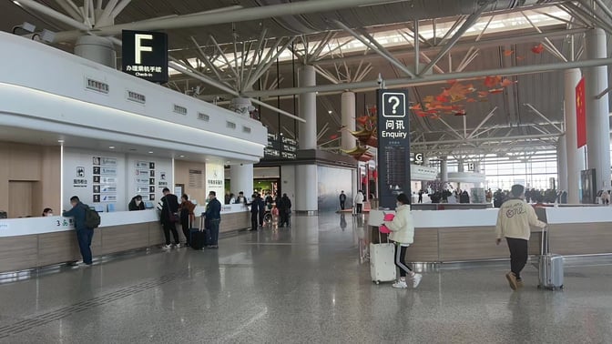 The check-in area at Nanjing Lukou International Airport features multiple counters for passenger assistance and an enquiry section nearby.