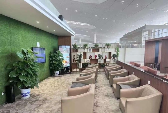 The V6 Business Lounge at Nanjing Lukou International Airport features comfortable seating with a display screen and decorative shelving.