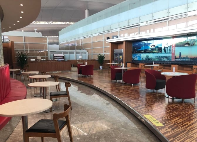 The V6 Business Lounge at Nanjing Lukou International Airport features seating areas with tables and chairs, adjacent to a service counter.