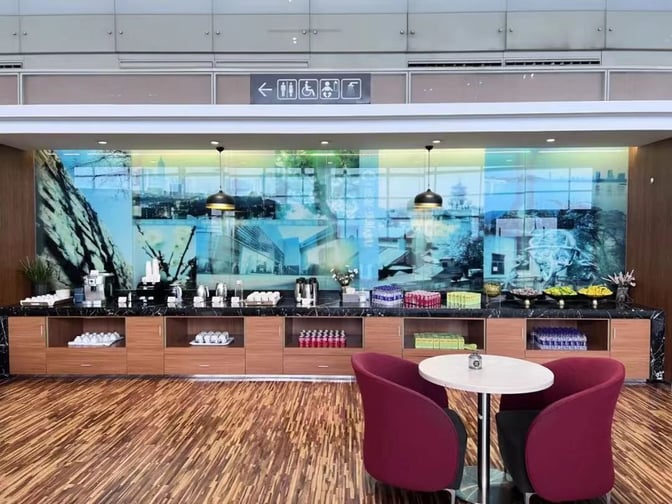 The V6 Business Lounge at Nanjing Lukou International Airport features a self-serve food and beverage station with seating nearby.
