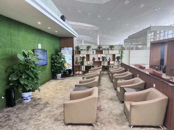 The seating area in V6 Business Lounge at Nanjing Lukou International Airport features comfortable chairs, a green wall, and decorative shelving.